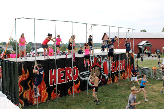 Image of 2012 Hero Rush Obstacle Course Race participants sliding down metal poles during the event