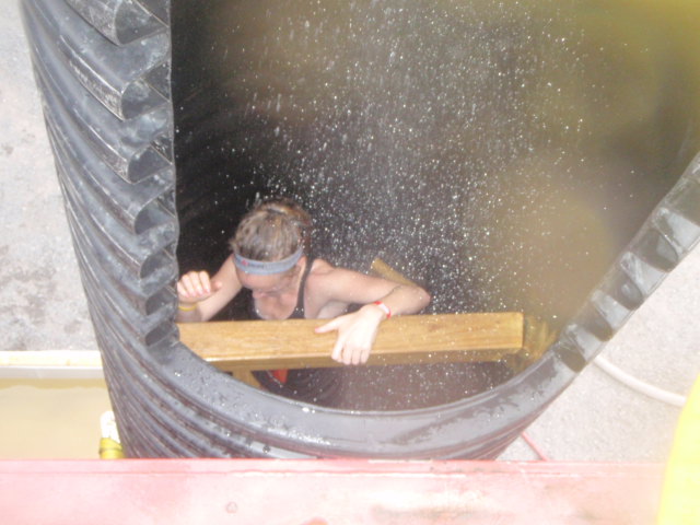 View of Heather Hart climbing down a tube while water rains from above during the 2012 Hero Rush Obstacle Course Race