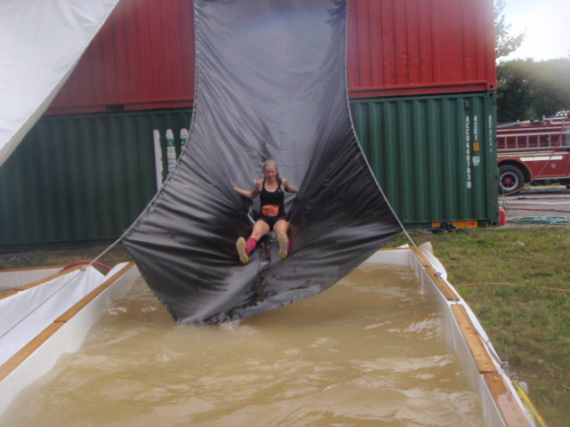 Heather Hart slides down a tarp into a pool of water during the 2012 Hero Rush Obstacle Course Race