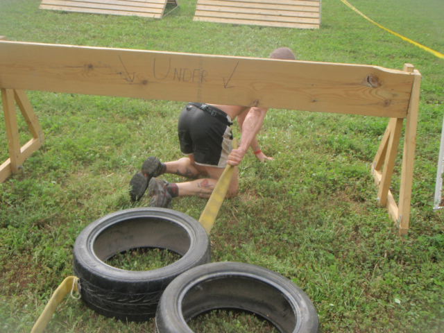 Geoffrey Hart drags tires attached to a fire hose under a wooden fence during the 2012 Hero Rush Obstacle Course Race