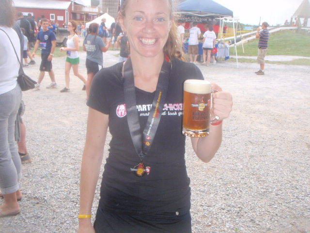 Heather Hart smiling and holding a beer wearing a finishers medal at the end of the 2012 Hero Rush Obstacle Course Race