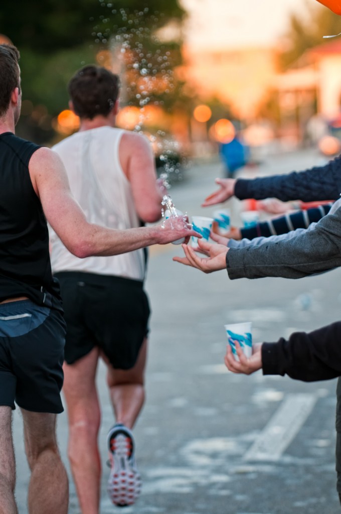 runners grabbing water from volunteers during a race