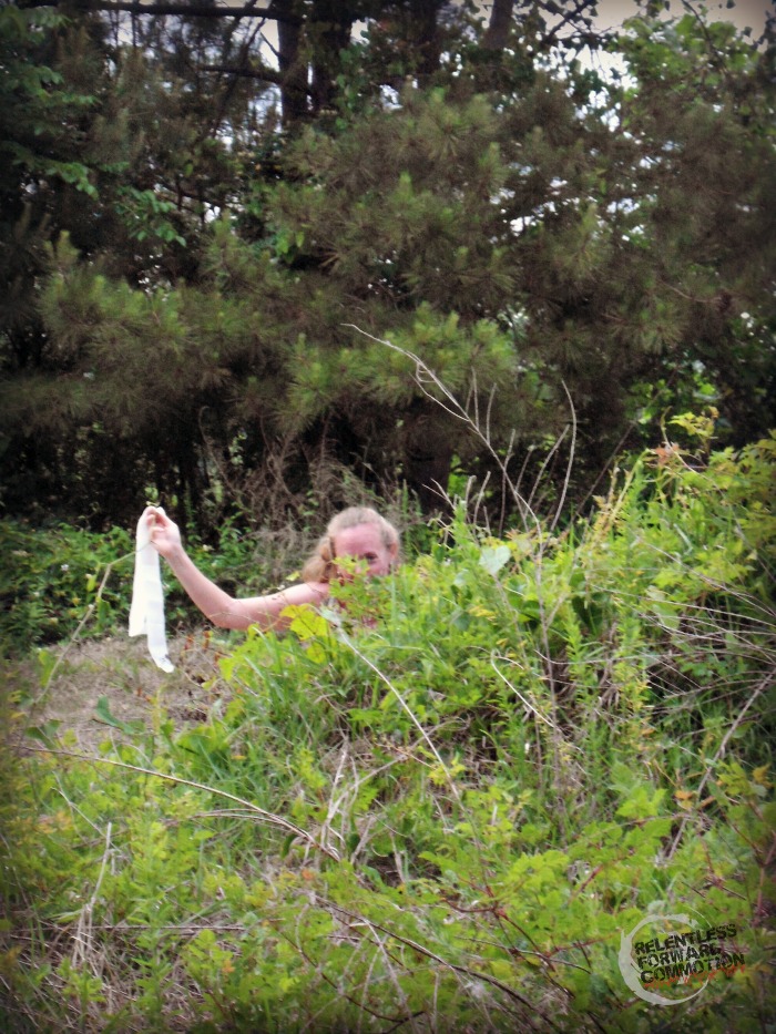 Photo of a trail runner ducking behind a bush to use the bathroom