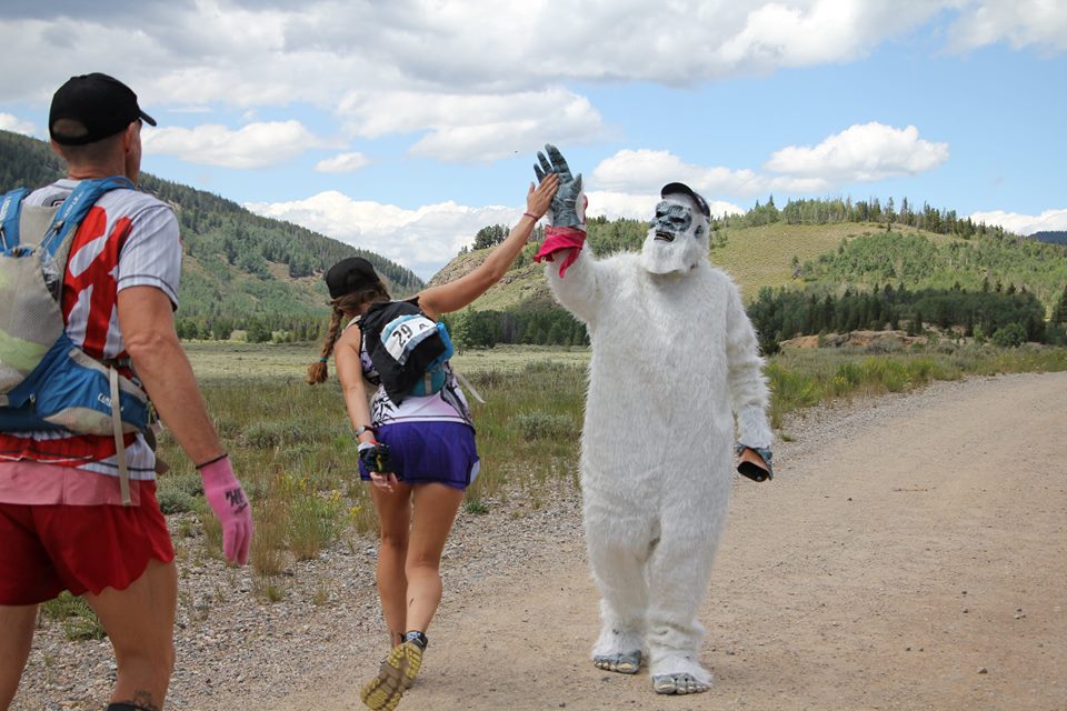 Heather Hart high fiving a yeti during the TransRockies Run 6 day Stage Race