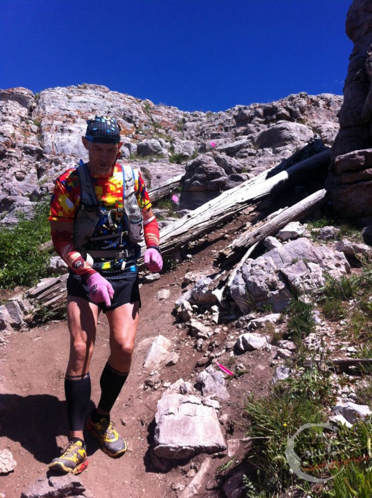 trail runner runs down a rocky steep hill 