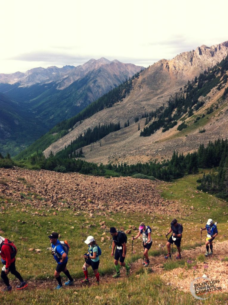 Runners climbing in a single line up a trail ascending a large mountain pass in Leadville Colorado during the Transrockies Stage Race
