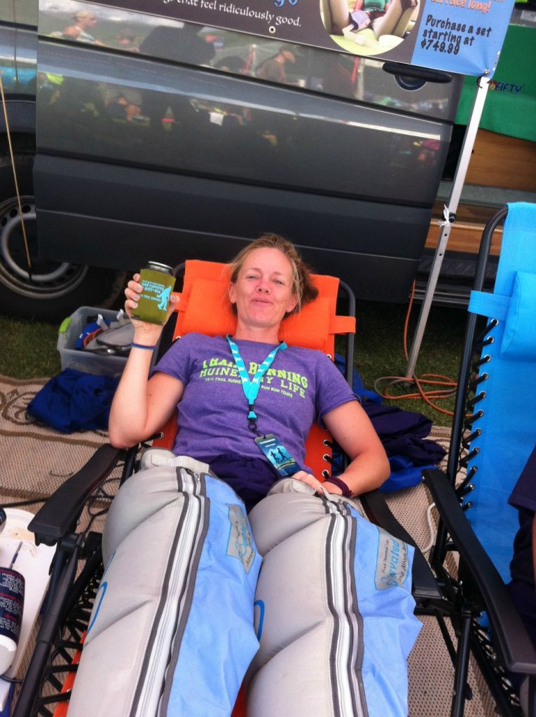 An ultrarunner enjoys relaxing in compression recovery boots while drinking a beer after the TransRockies Run stage race