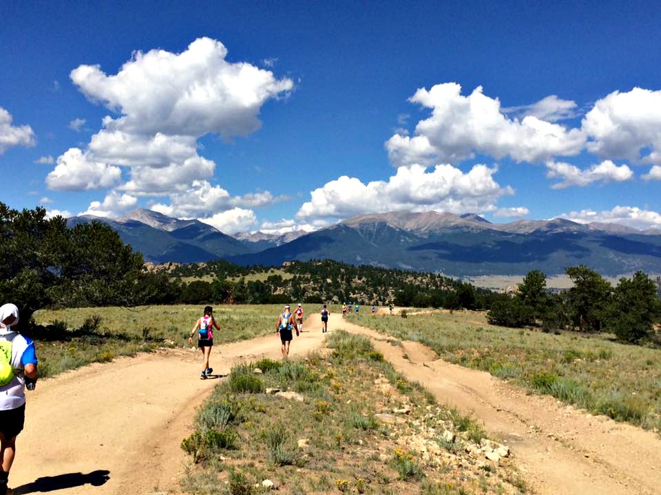 trail marathon runners running down a dirt path in the mountains of Colorado 