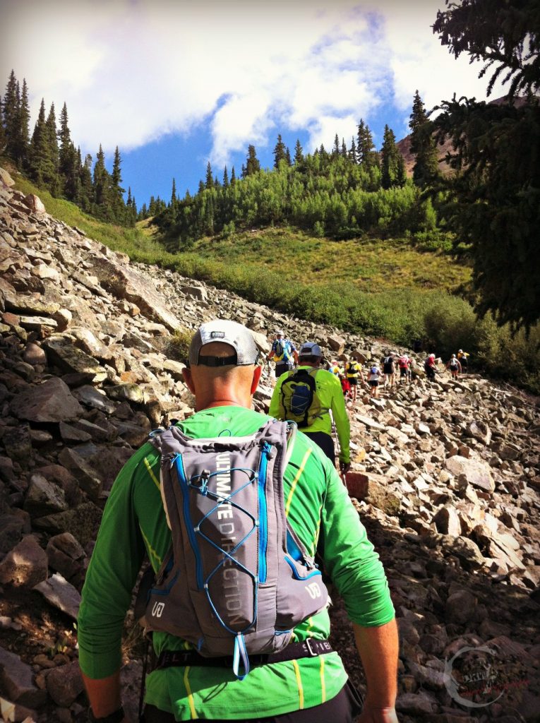 Ultramarathon runners climbing a long, narrow, rock covered trail in the Colorado Rocky mountains during a race