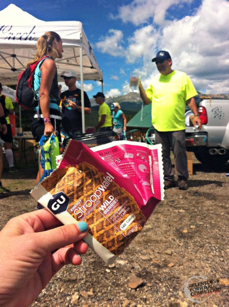 Image of a runner holding up a GU Stroopwafel at an aid station during a trail race