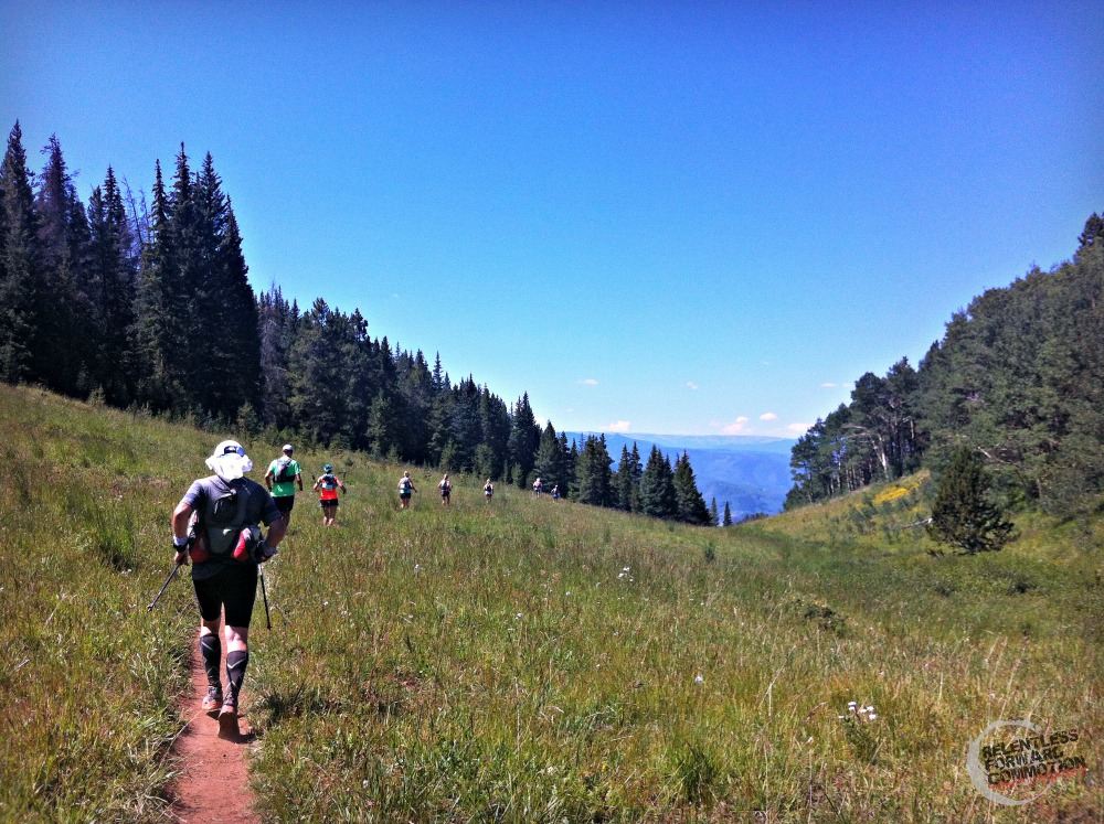 Group of runners in a race running down a narrow single track trail, running downhill