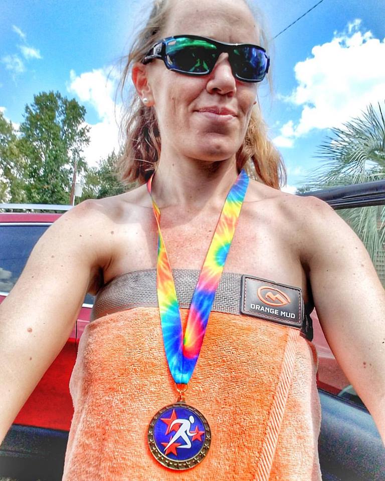 Woman wearing finishers medal and only a towel, after running a naked 5K 