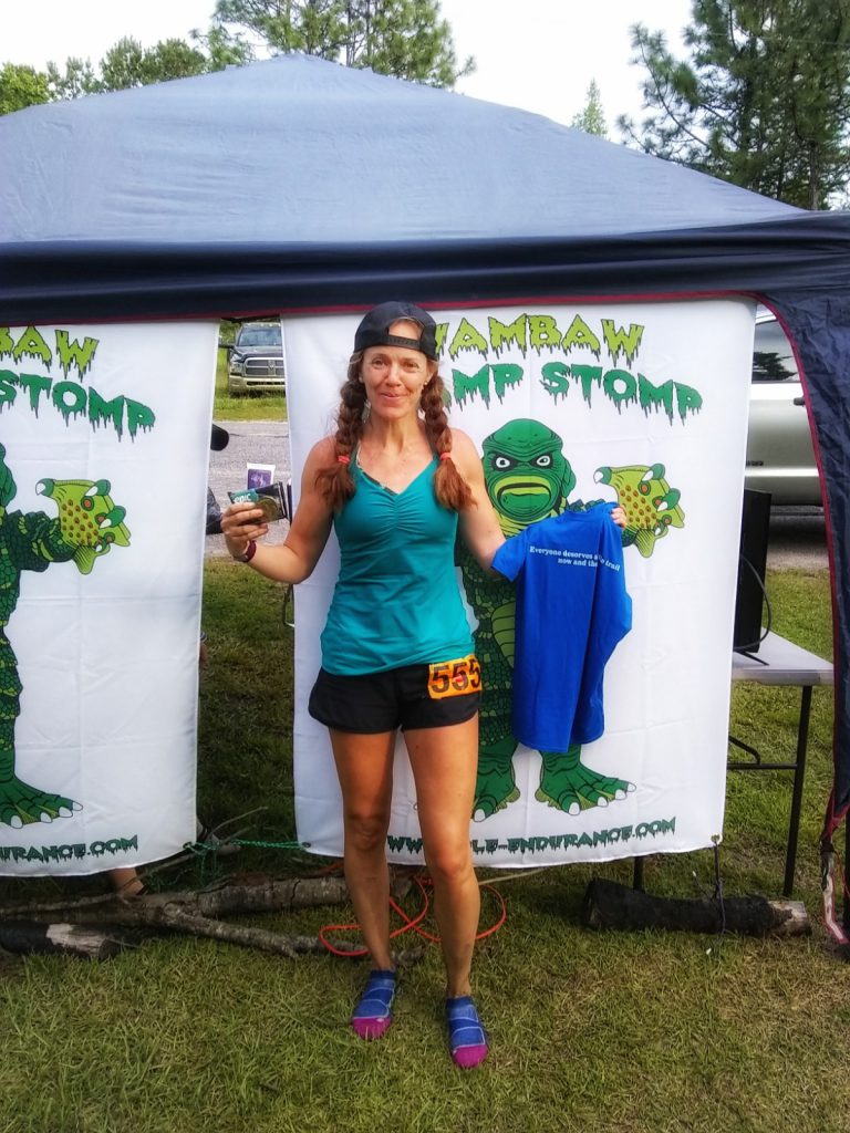 Heather Hart smiling at the finish line of the Wambaw Swamp Stomp 50 miler, a successful finisher after a string of running DNF's