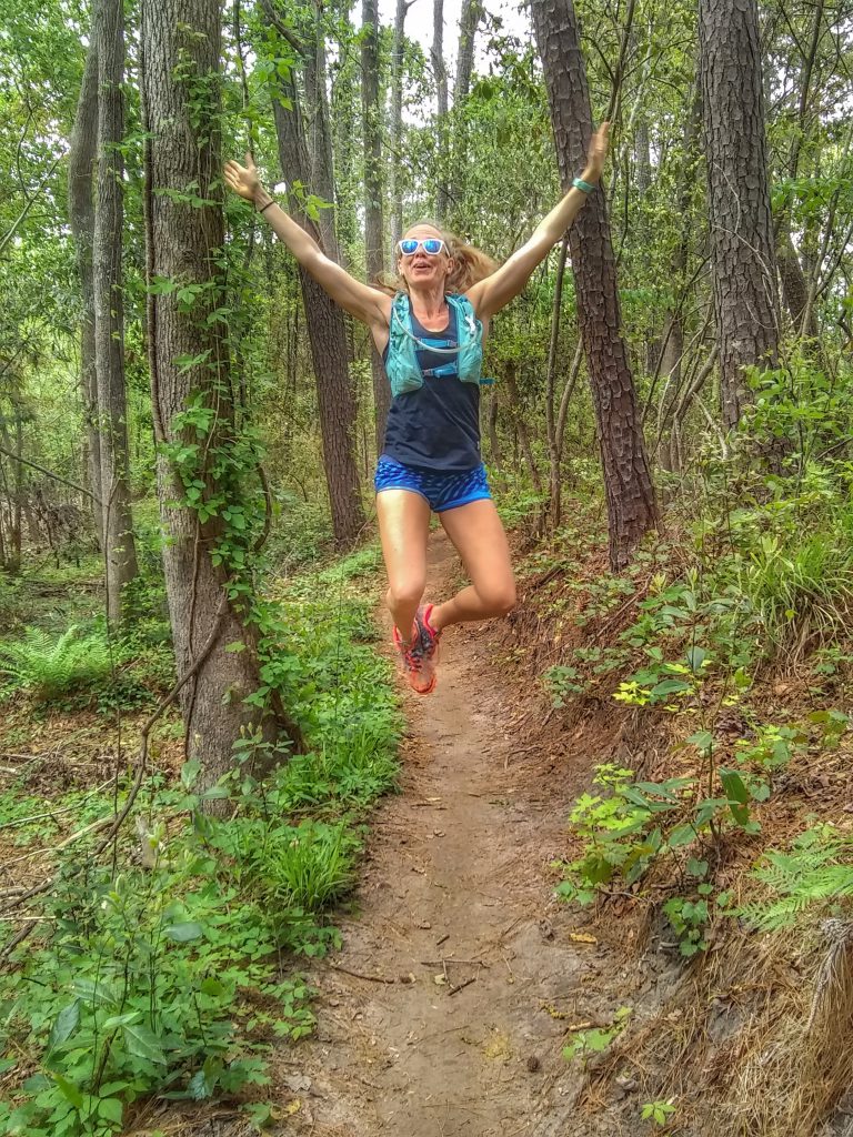 Heather Hart jumping for joy during the middle of a trail run