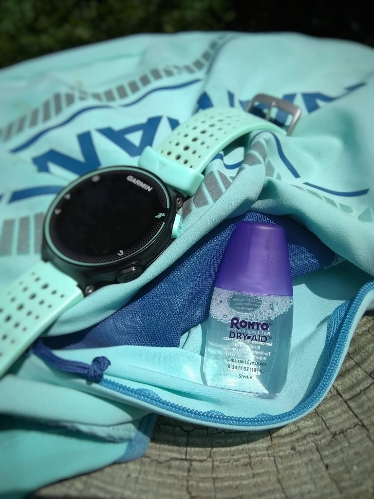 Image of an ultrarunning vest, GPS watch, and small bottle of eye drops