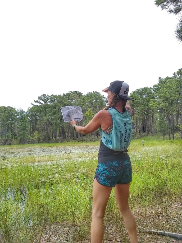 Heather Hart on a trail looking for a map while pretending to be lost.  8 Trail Running Safety Tips Every Runner Needs to Know