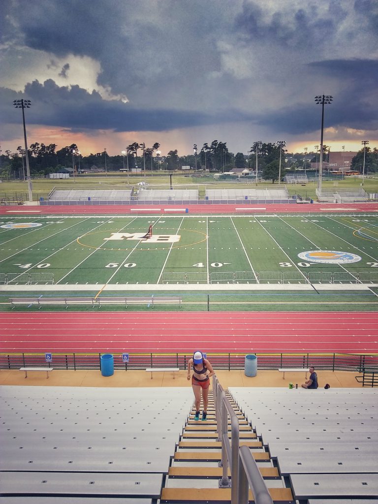 Runner sprinting up stadium stairs at a track and field track during a workout