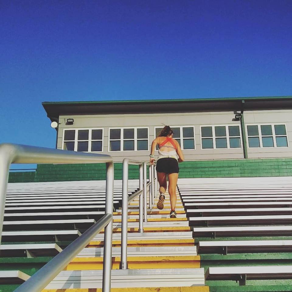 Image of a runner running up stadium stairs at a football field during a training workout 