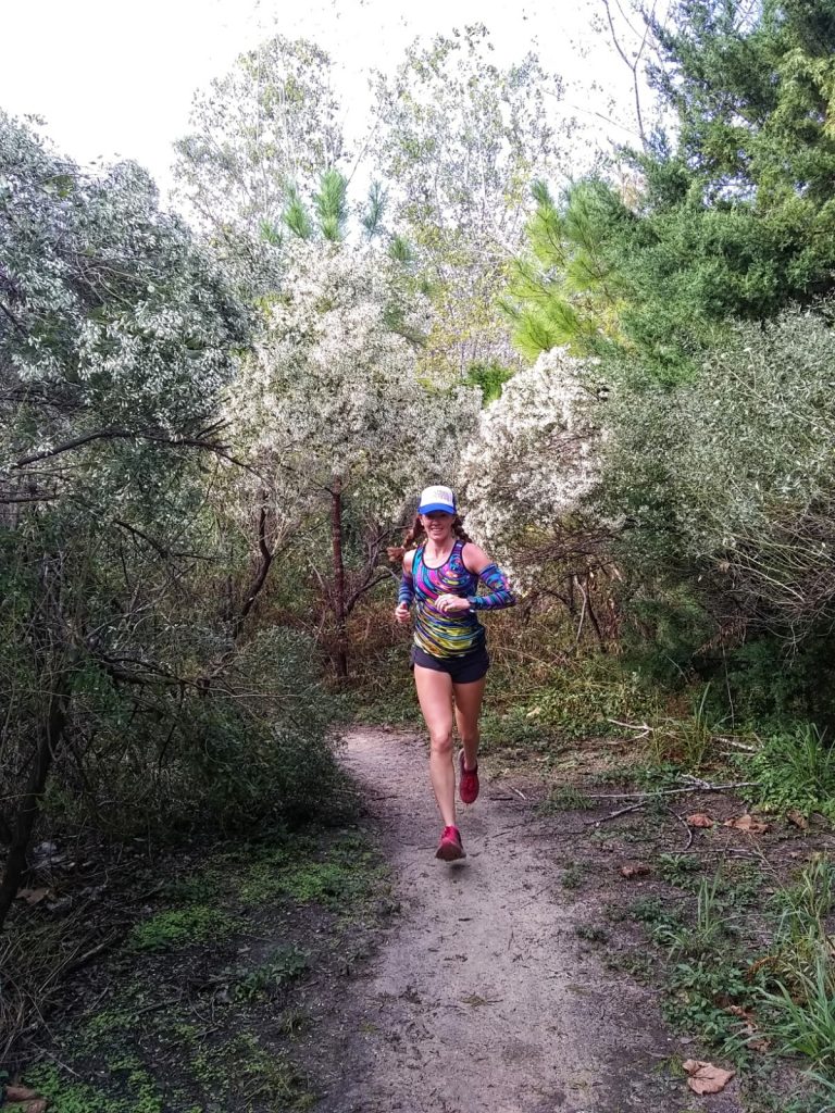 Heather Hart running down a trail surrounded by blooming trees