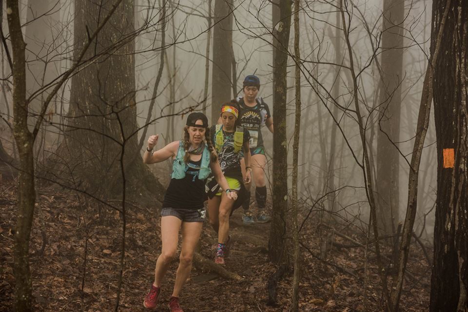 Runners running down the trail in the forest in the fog during an ultramarathon