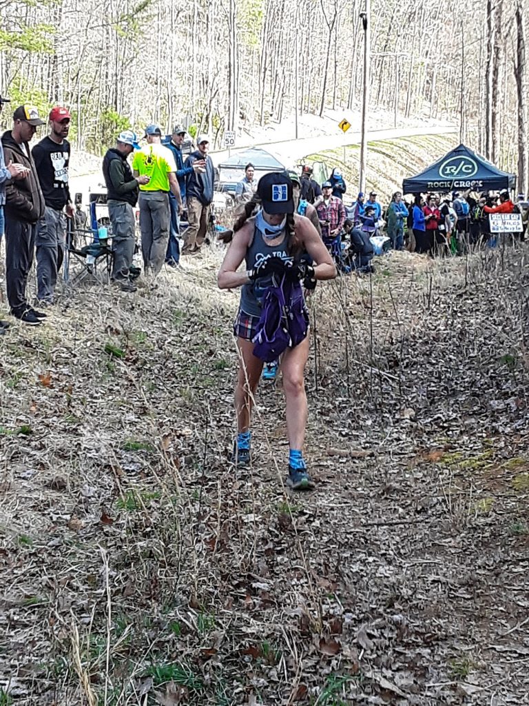 Ultrarunner climbing a hill out of an aid station during an ultramarathon