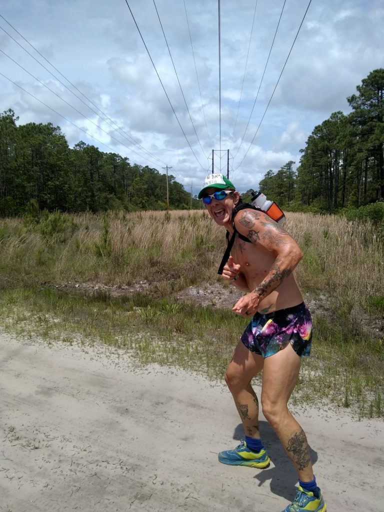 Geoffrey Hart running down a dirt road wearing a hydration pack training for an ultramarathon 