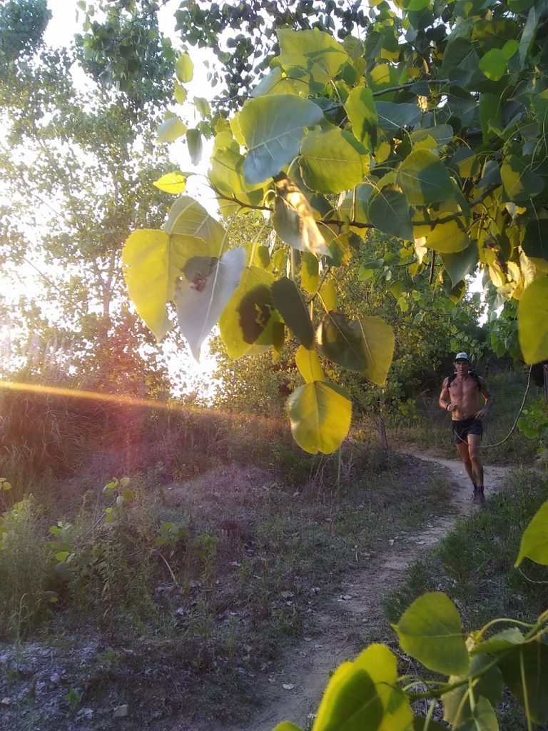 Geoffrey Hart runs down a beautiful trail at sunset 