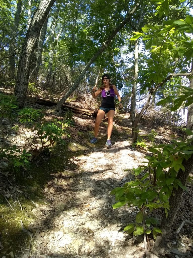 Woman running down a steep mountain trail 