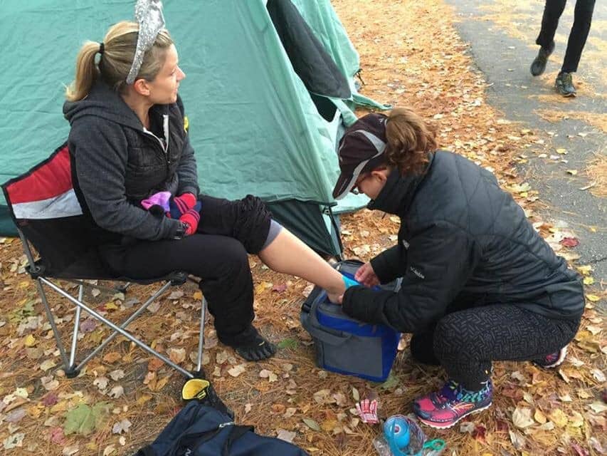 Crew member tapes runners foot during ultramarathon