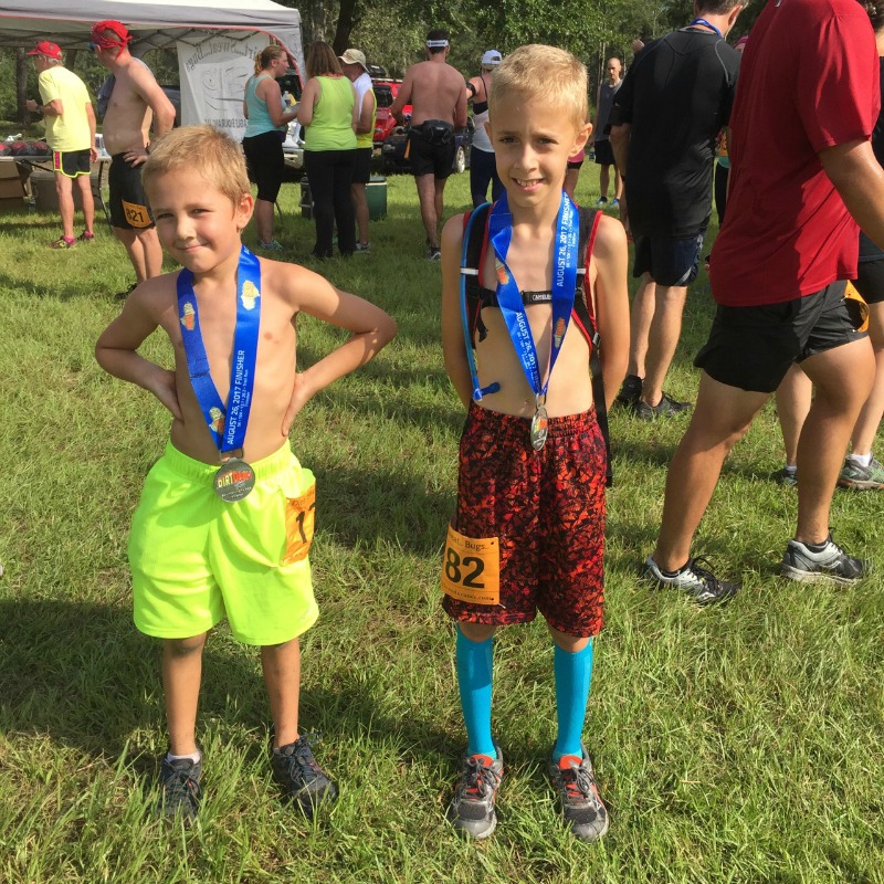 two young kids wearing finishers medals at the end of a 5K