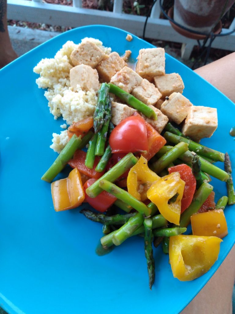Image of a plate of food containing couscous, tofu, and vegetables on a bright blue plate