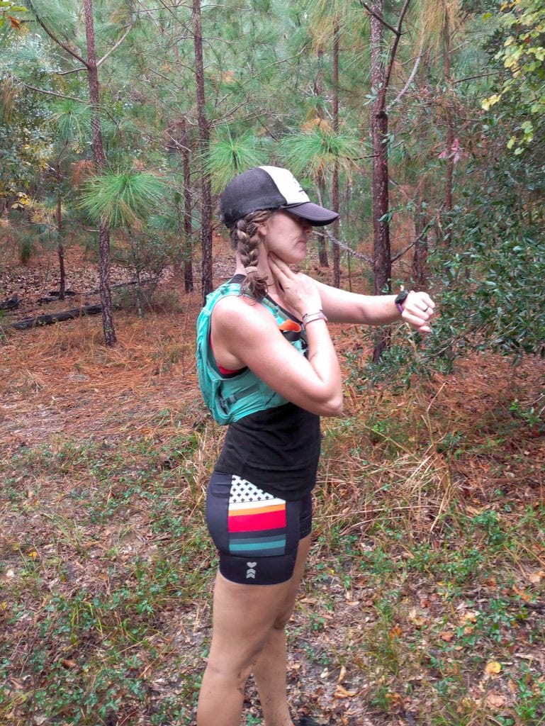 A runner stops to check her heart rate by feeling for her pulse