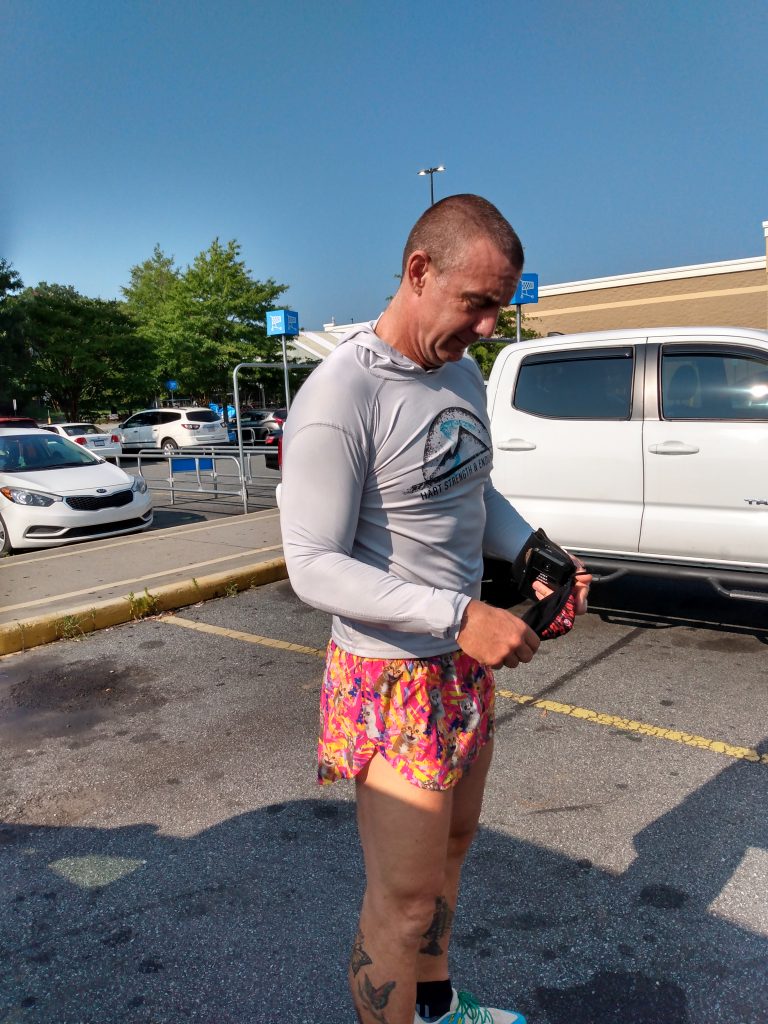 Geoffrey Hart in parking lot wearing too tiny shirt