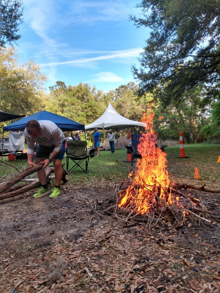 man builds campfire at a trail race