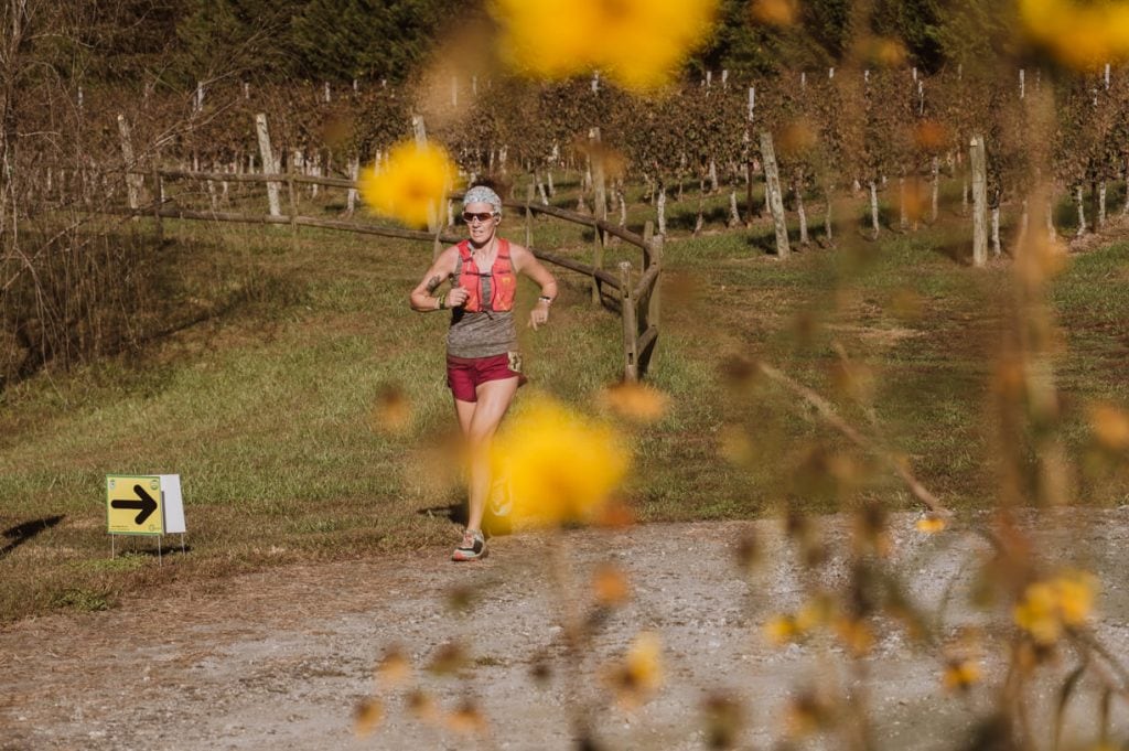 Image of ultramarathon runner during a race, running through a vineyard 