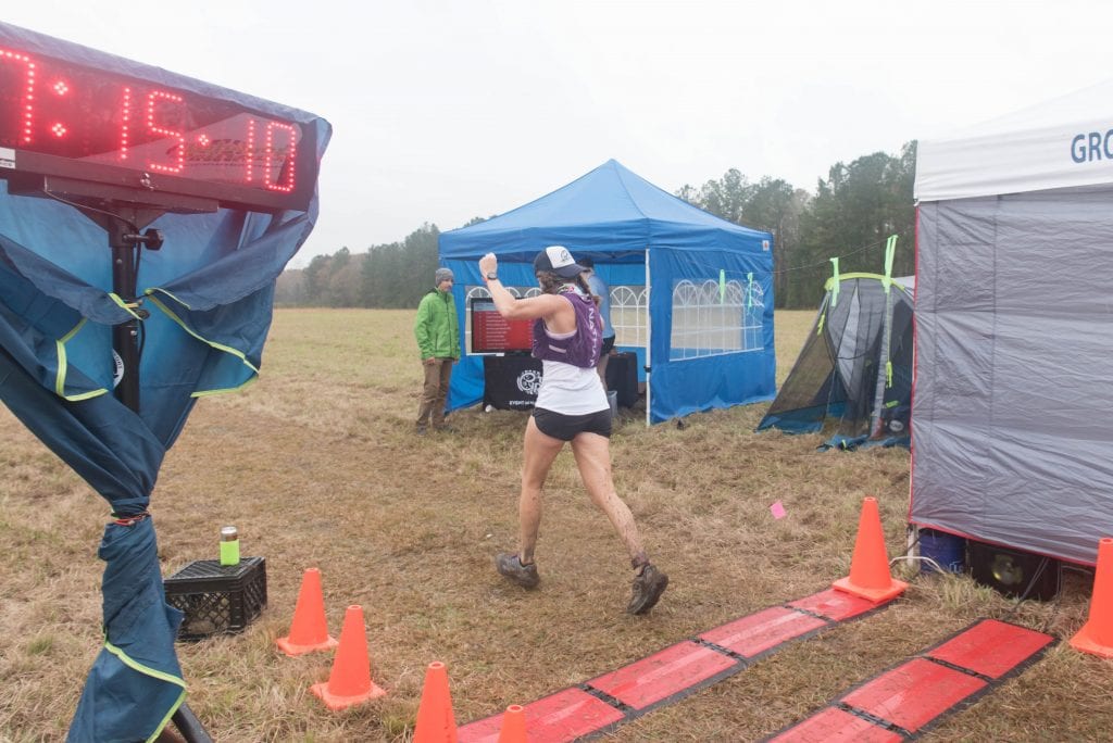 Trail Runner arms raised high in celebration as she crosses a finish line