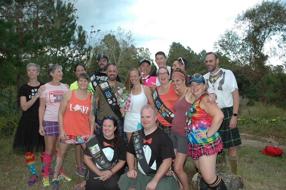 Image of a group of Hash House Harriers members posing for a photo at a wedding of two of the hashers. 