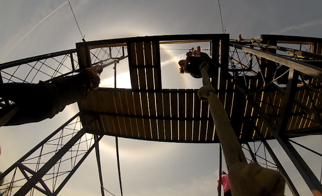 View from below, looking up to a woman crawling up a rope during the the Hero Rush OCR