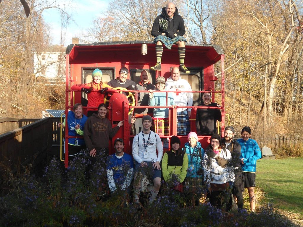 Group of hashers from a hash house harriers kennel posing for a picture on a railroad caboose
