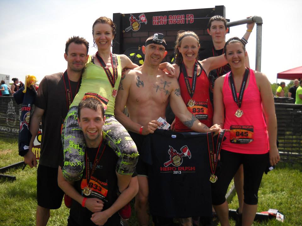 Smiling picture of finishers, wearing medals and holding t-shirts after competing in the the Hero Rush OCR
