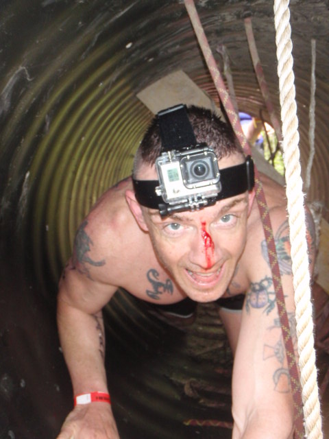 Geoffrey Hart crawls through tube during the the Hero Rush OCR with blood pouring down his forehead after a GoPro injury 