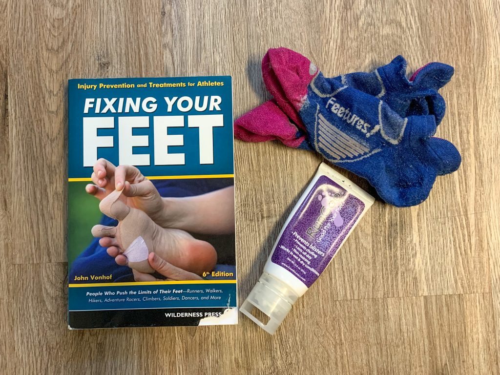 An image of three things that are helpful in lieu of waterproof trail running shoes: the book "Fix Your Feet", wool running socks, and "RunGoo" lubrication