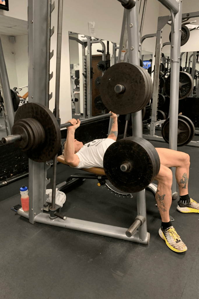 Geoffrey Hart bench pressing in a Smith rack machine at a gym