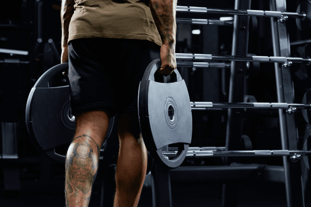 Stock photo of a man carrying two forty-five pound plates in a "weighted carry" exercise