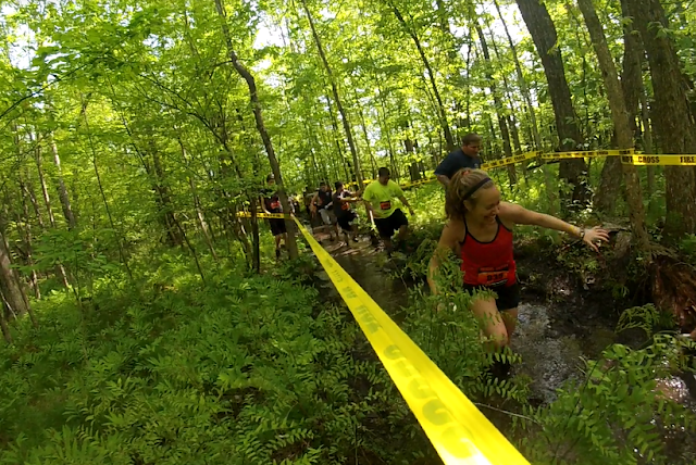 Heather Hart and other obstacle course race athletes stomping through the mud in the forest during the Hero Rush OCR