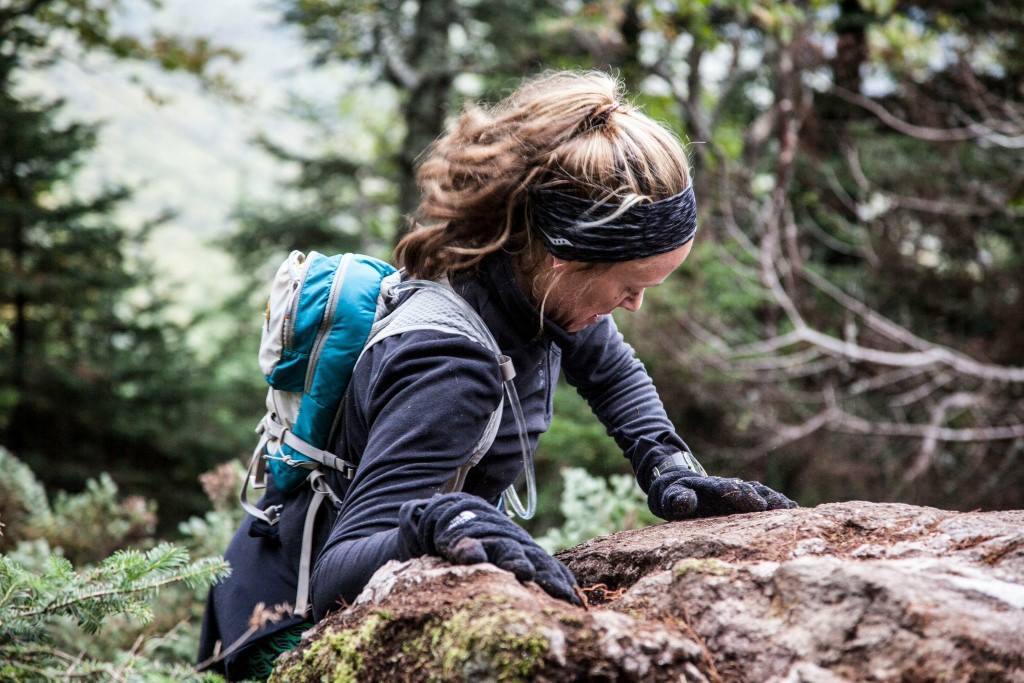 trail running works a variety of muscles, sometimes including your upper body.  Image of Heather Hart using her upper body to climb a large rock while trail running