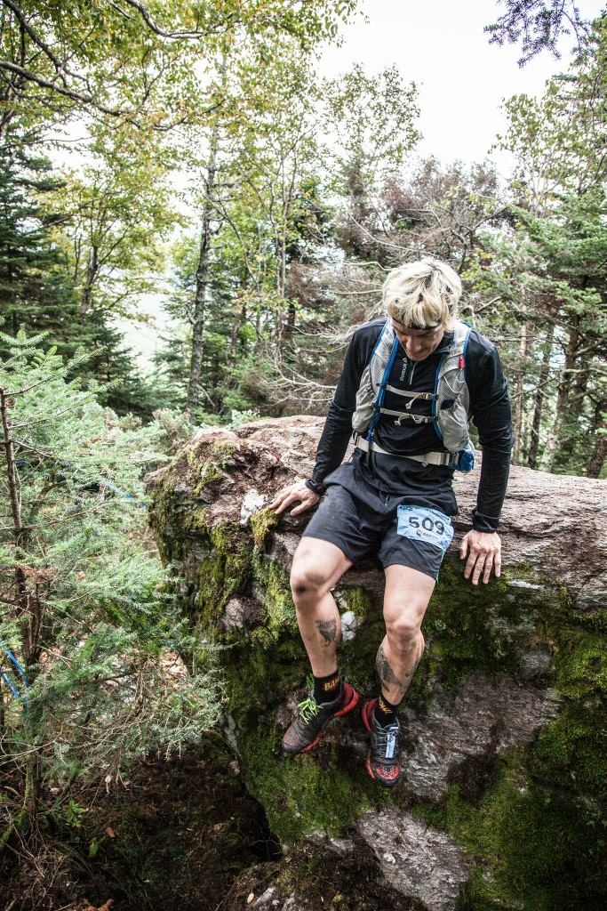 Geoffrey Hart climbing down off of a big rock in the middle of a trail race