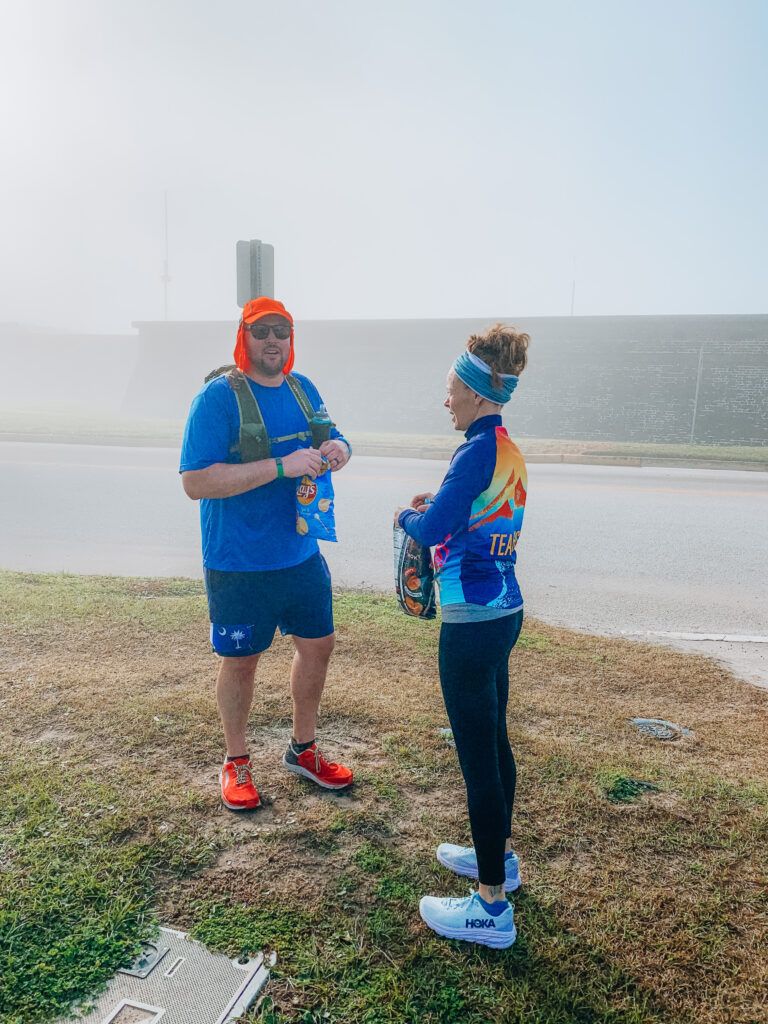 Heather Hart hands a bag of potato chips to a runner while crewing during the Charleston 100 mile ultramarathon