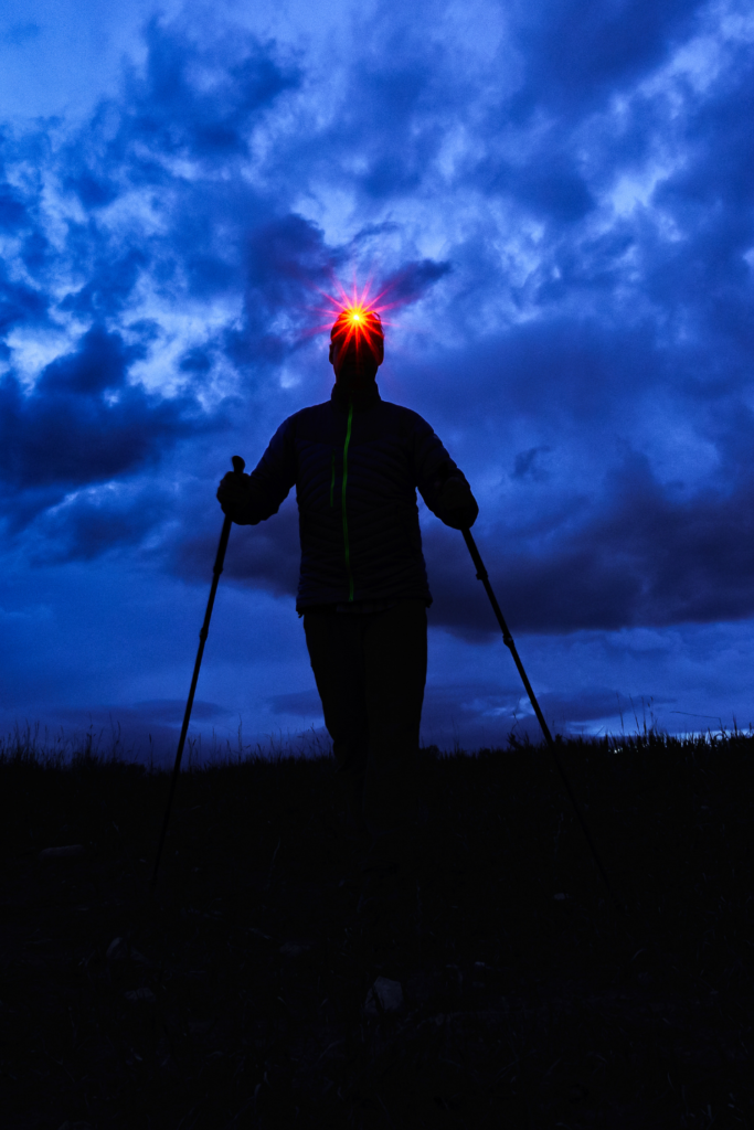 Ultrarunner running at night wearing a headlamp featuring a red light