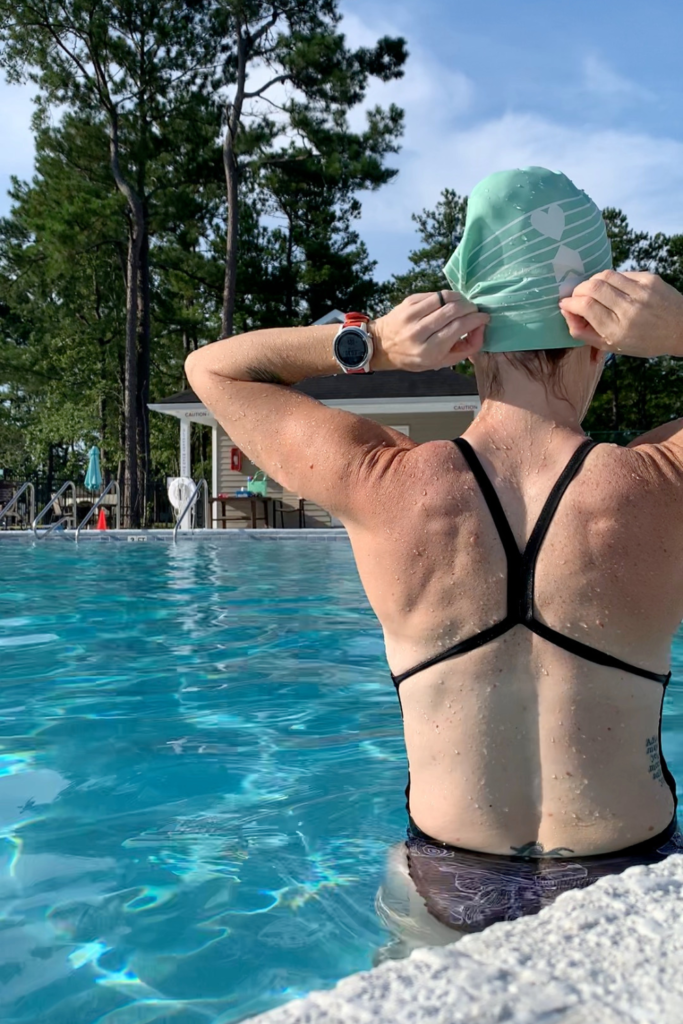 Runner Heather Hart pulling on a swim cap while in a swimming pool getting ready to swim laps as a form of cross training for runners